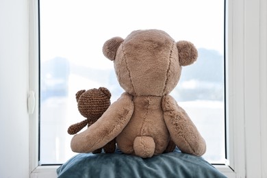 Photo of Two cute teddy bears near window indoors, back view