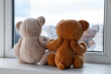 Photo of Two cute teddy bears near window indoors, back view