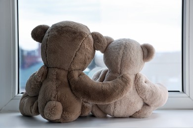 Photo of Two cute teddy bears near window indoors, back view