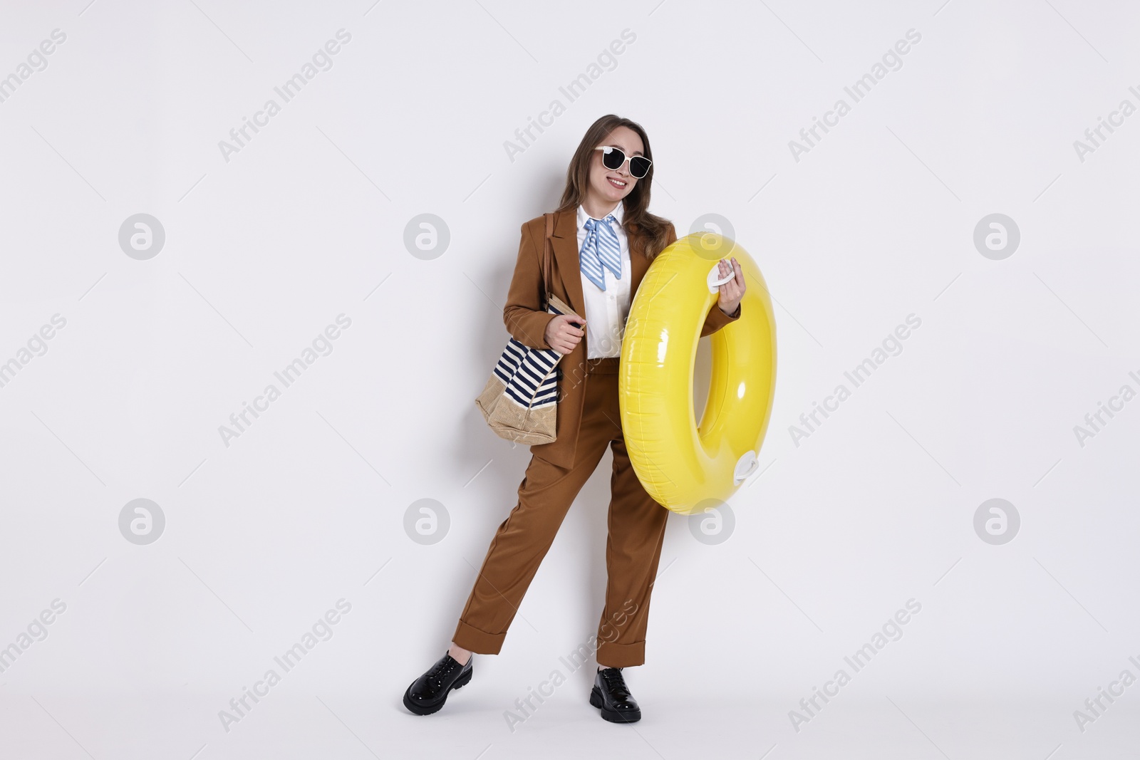 Photo of Businesswoman with inflatable ring, bag and sunglasses on white background