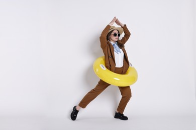 Photo of Businesswoman with inflatable ring, straw hat and sunglasses on white background