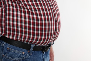 Photo of Overweight man in tight shirt on white background, closeup. Space for text