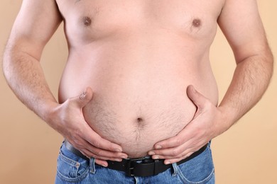 Photo of Man with excessive belly fat on beige background, closeup. Overweight problem