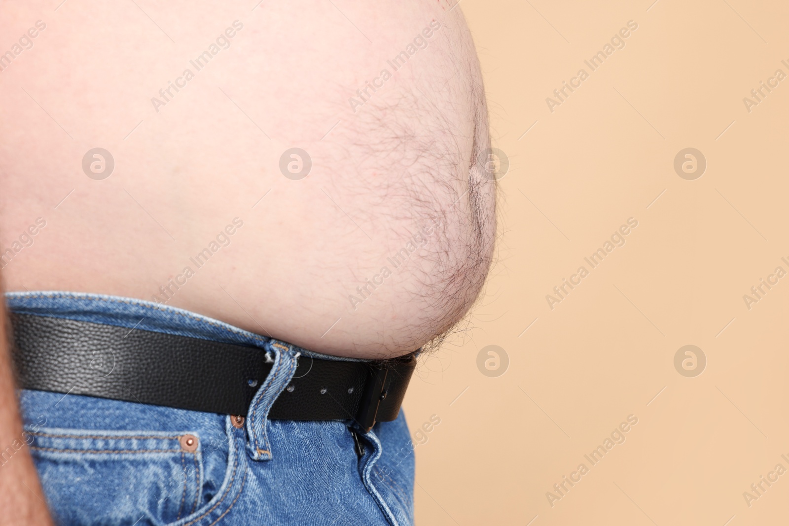 Photo of Overweight problem. Man with excessive belly fat on beige background, closeup. Space for text