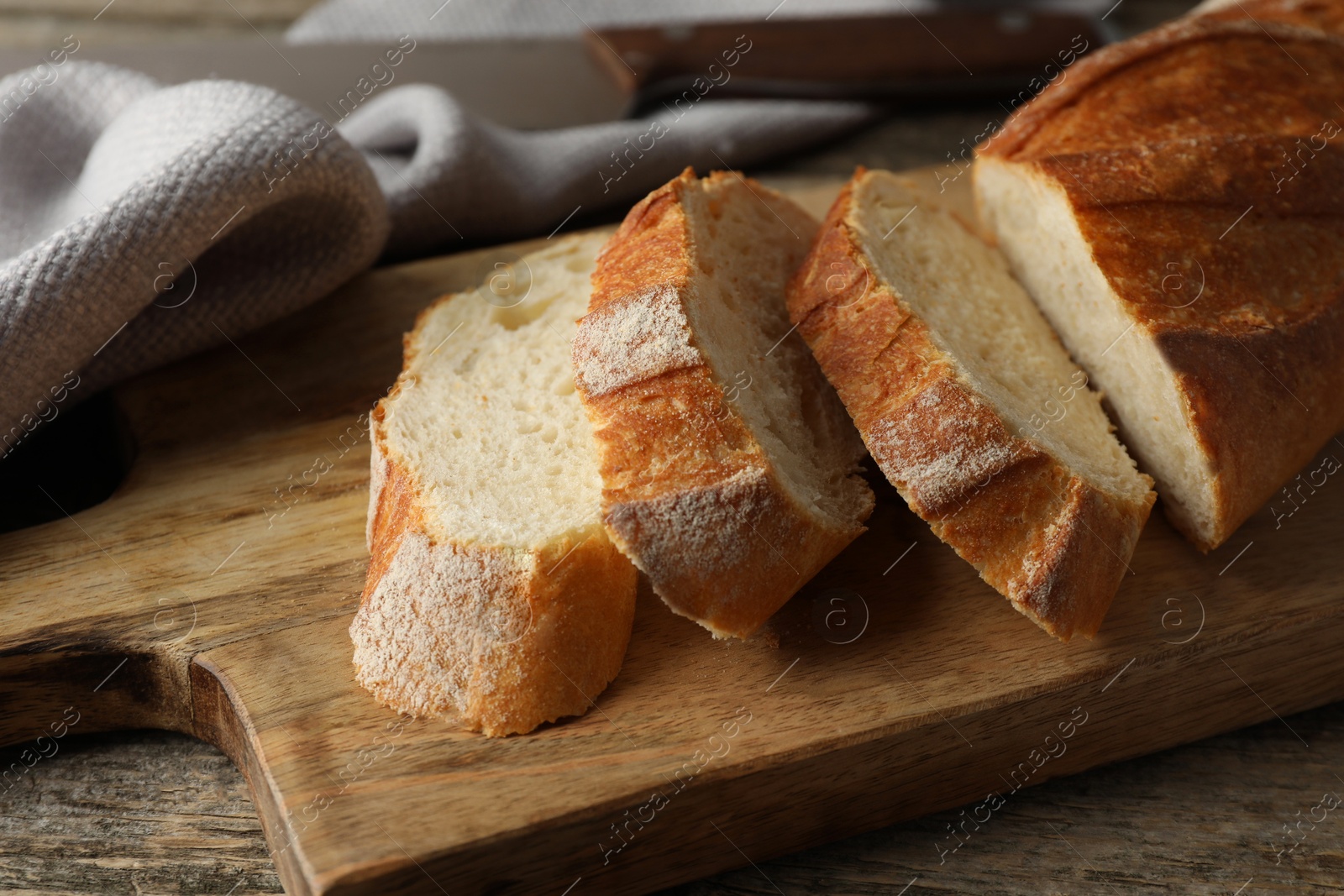 Photo of Pieces of fresh baguette on wooden table, closeup