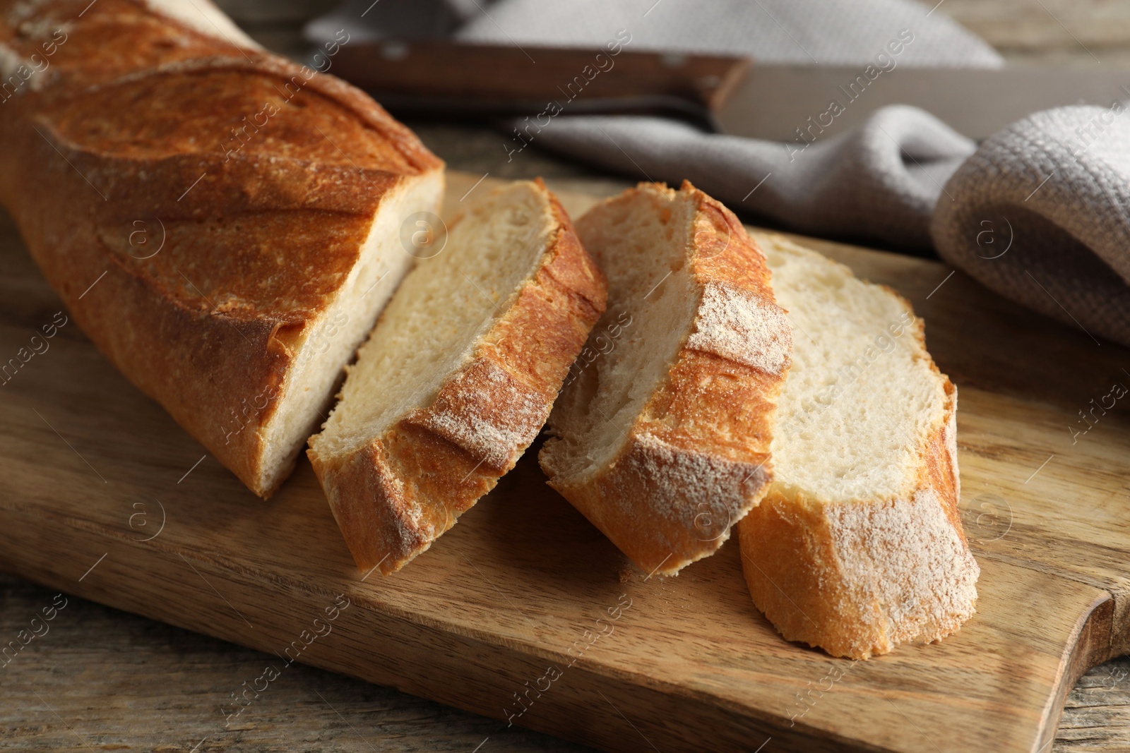 Photo of Pieces of fresh baguette on wooden table, closeup