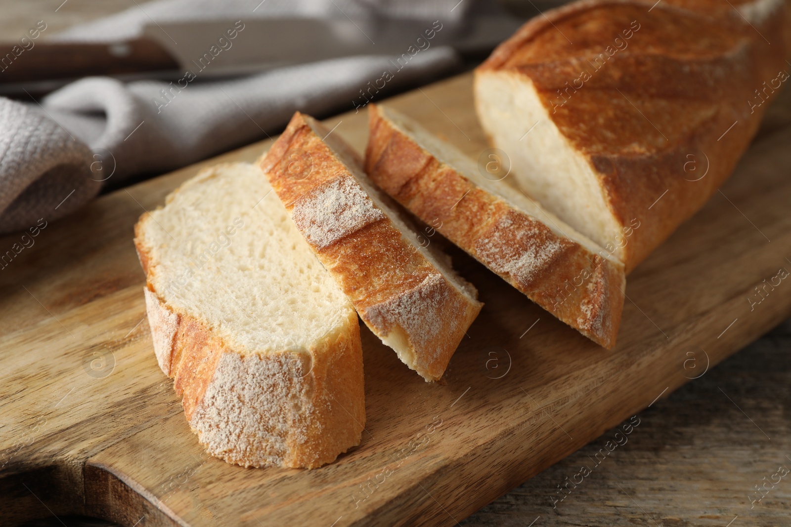 Photo of Pieces of fresh baguette on wooden table, closeup