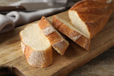 Photo of Pieces of fresh baguette on wooden table, closeup