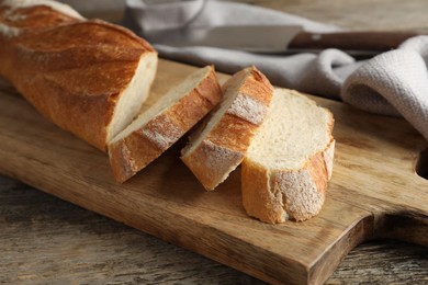 Photo of Pieces of fresh baguette on wooden table, closeup