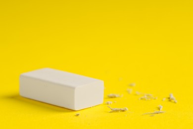 Photo of One eraser and scraps on yellow background, closeup. Space for text