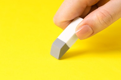 Photo of Woman using eraser on yellow background, closeup. Space for text