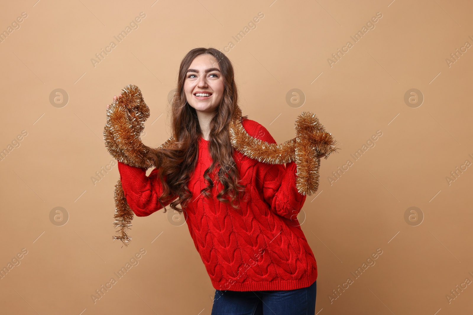 Photo of Happy young woman with tinsel on beige background