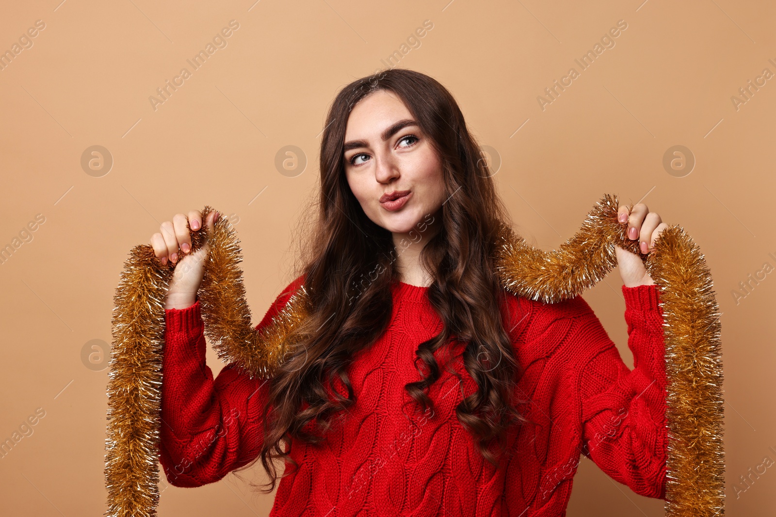 Photo of Beautiful young woman with tinsel on beige background