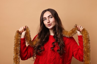 Photo of Beautiful young woman with tinsel on beige background