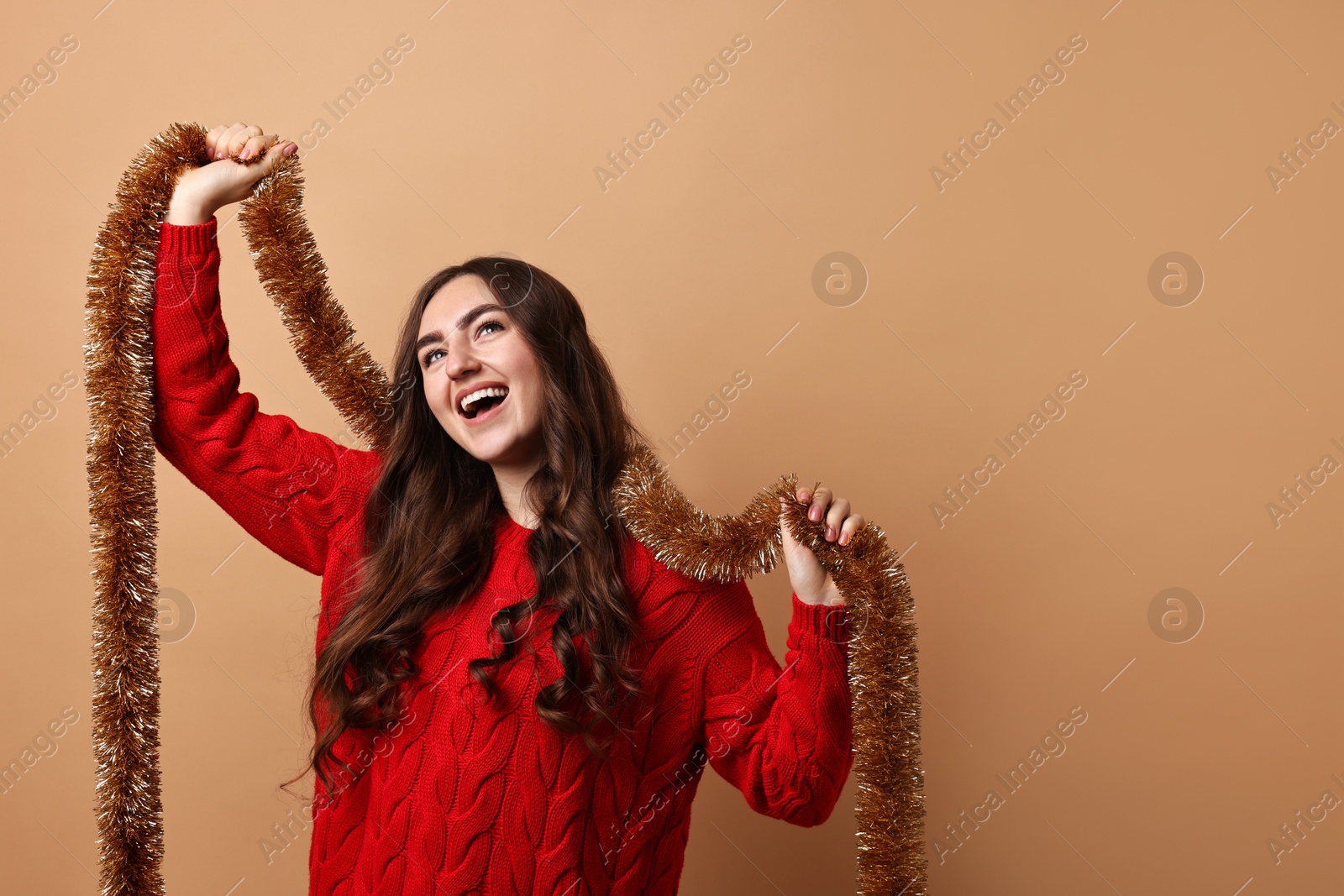 Photo of Happy young woman with tinsel on beige background. Space for text