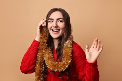 Photo of Happy young woman with tinsel on beige background