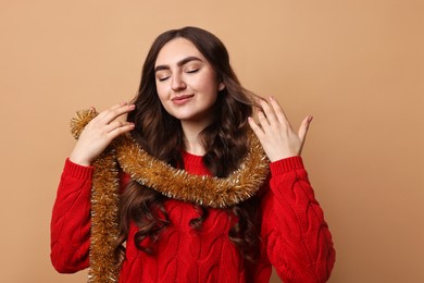 Photo of Beautiful young woman with tinsel on beige background