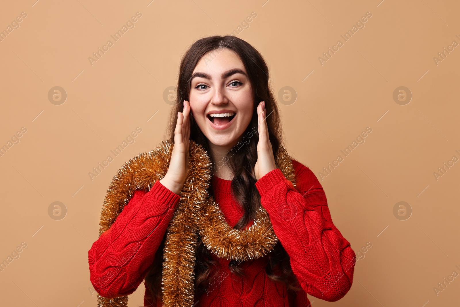 Photo of Happy young woman with tinsel on beige background