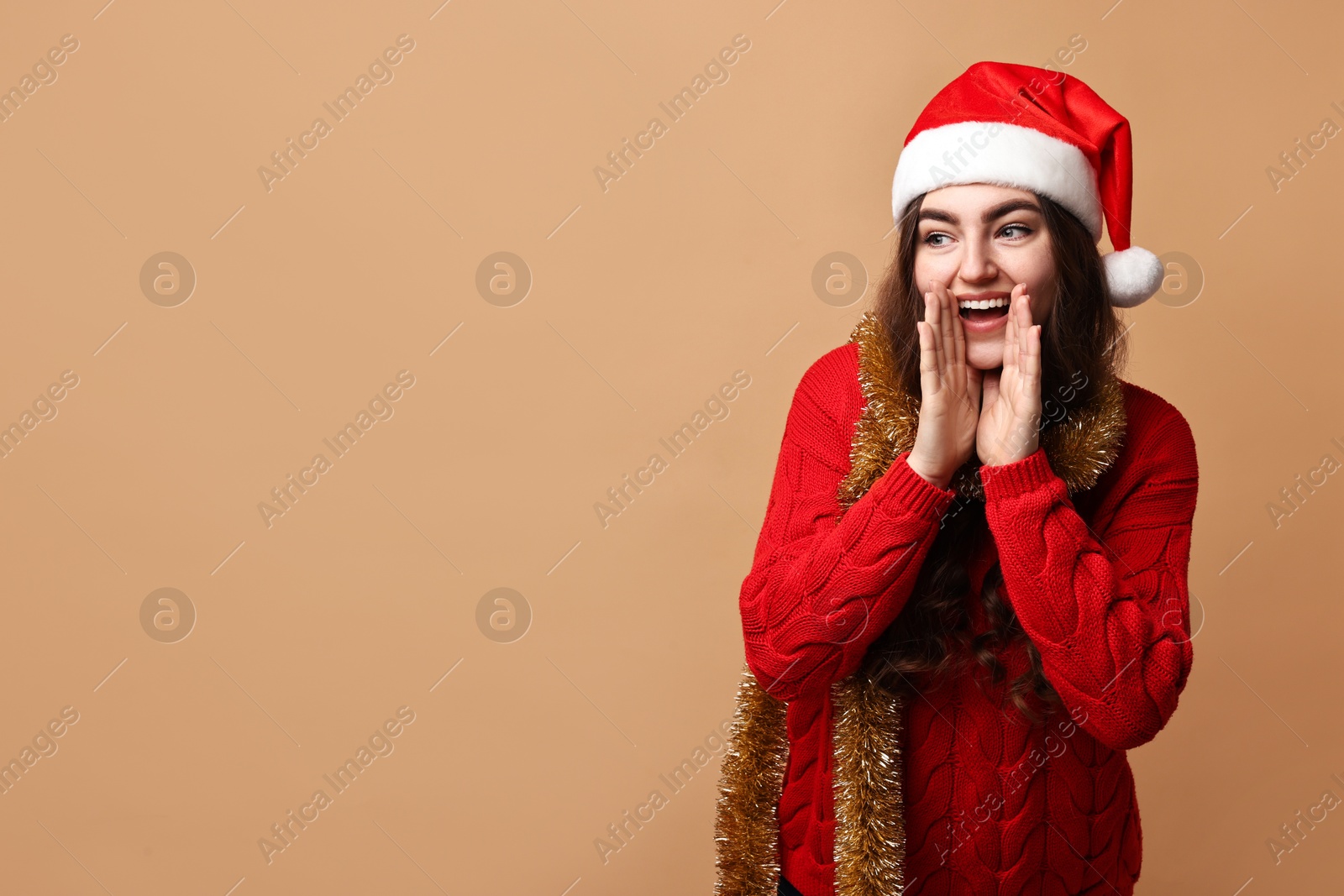 Photo of Happy young woman with tinsel and Santa hat on beige background. Space for text