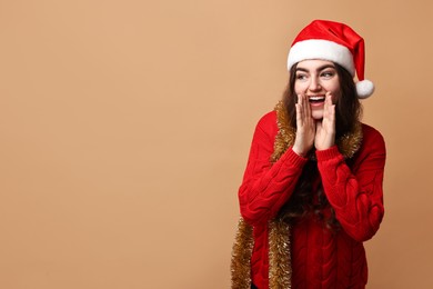 Photo of Happy young woman with tinsel and Santa hat on beige background. Space for text