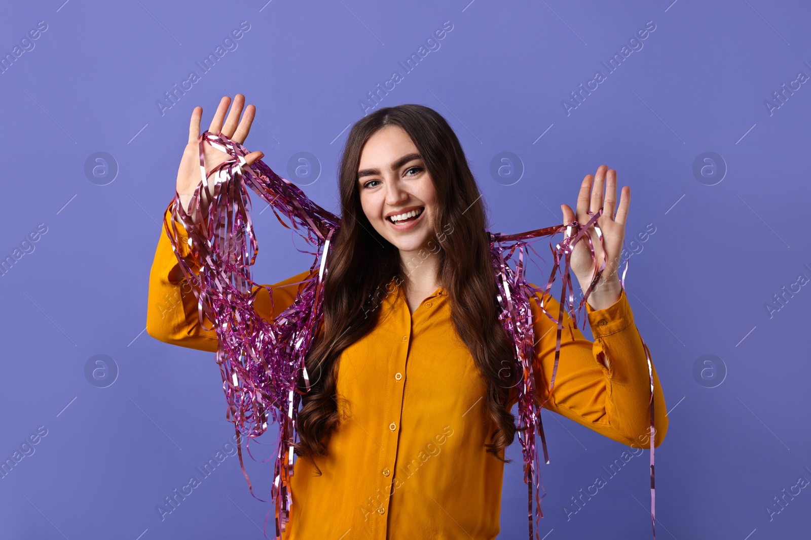 Photo of Happy young woman with tinsel on purple background