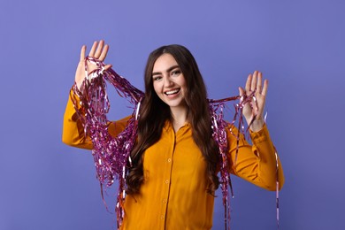 Photo of Happy young woman with tinsel on purple background