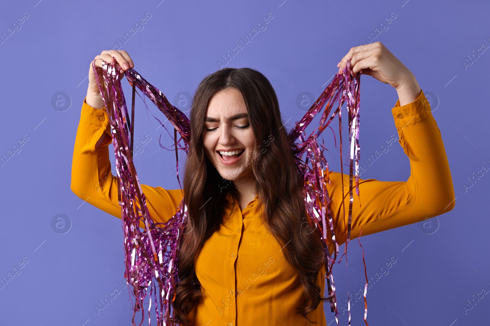 Photo of Happy young woman with tinsel on purple background