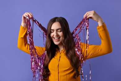 Photo of Happy young woman with tinsel on purple background