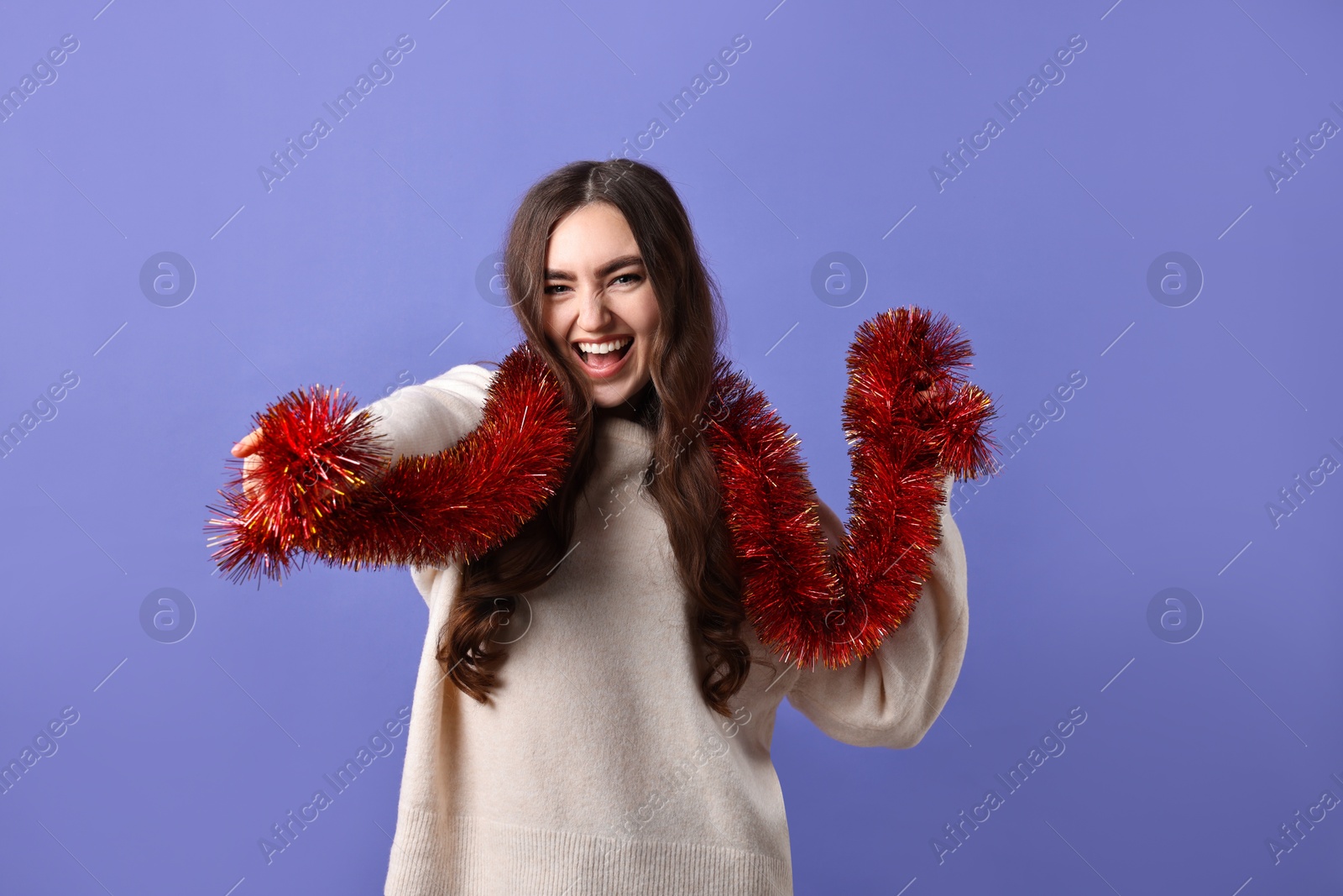 Photo of Happy young woman with tinsel on purple background