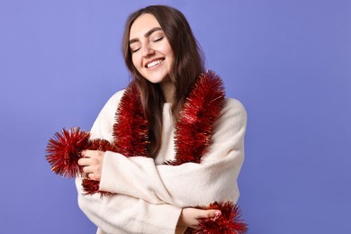 Photo of Happy young woman with tinsel on purple background