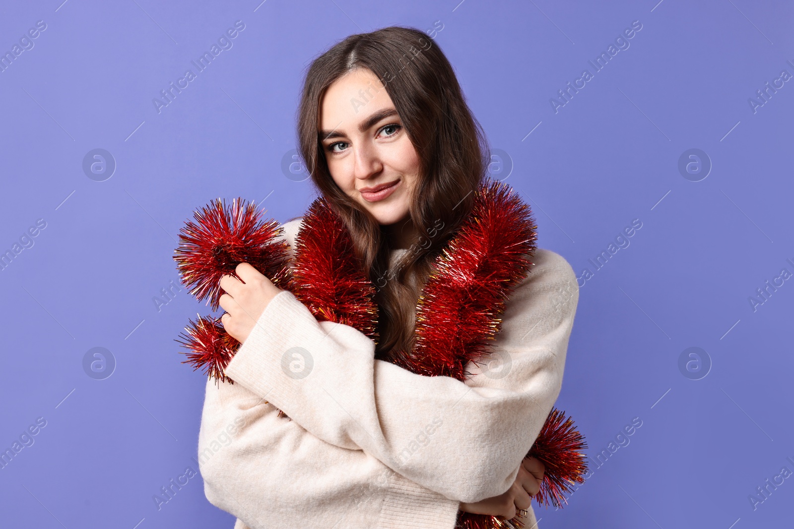 Photo of Beautiful young woman with tinsel on purple background