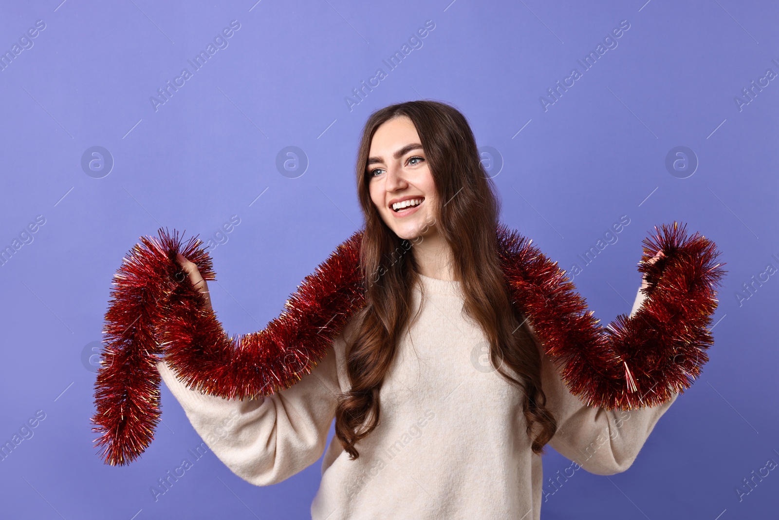 Photo of Happy young woman with tinsel on purple background