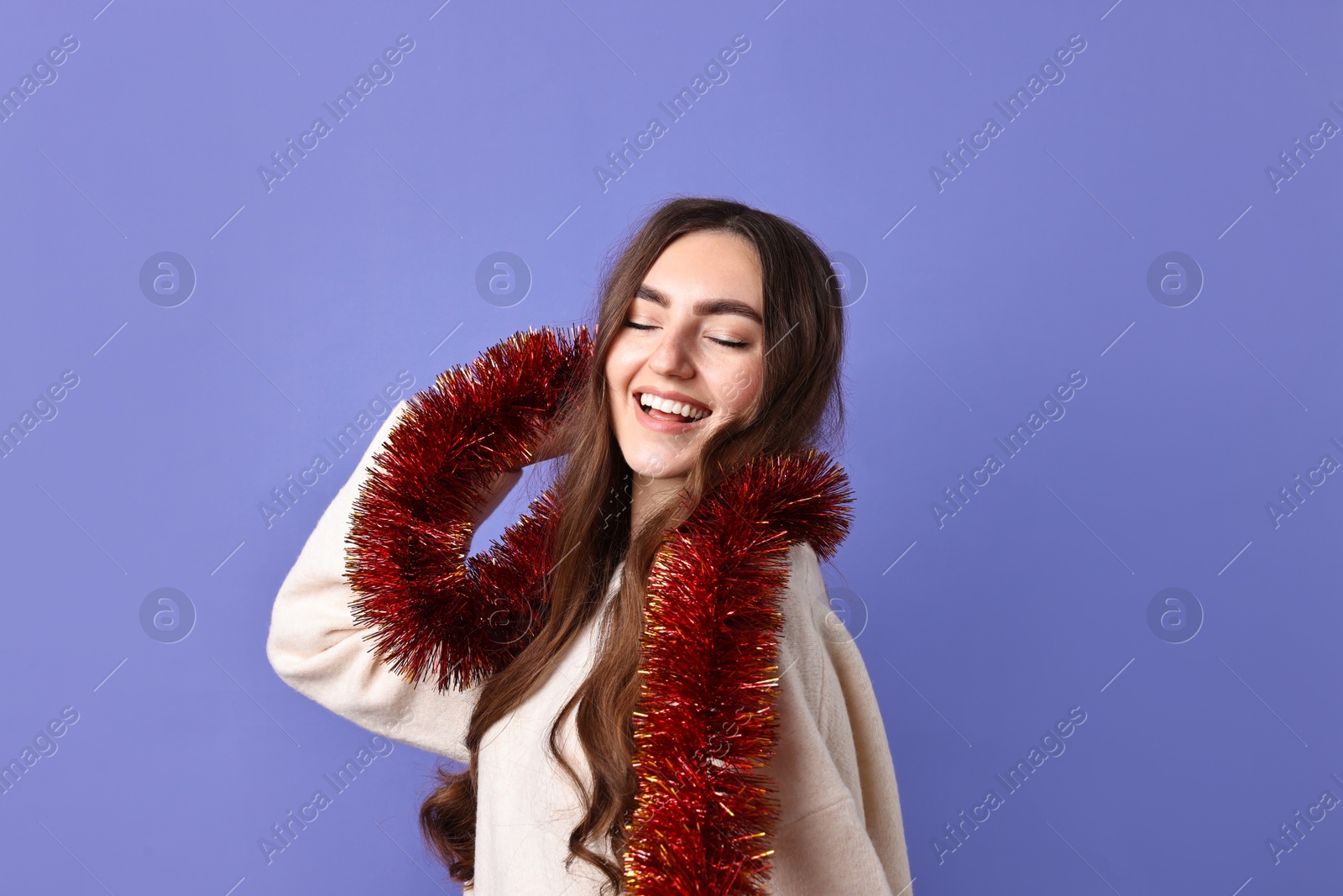 Photo of Happy young woman with tinsel on purple background