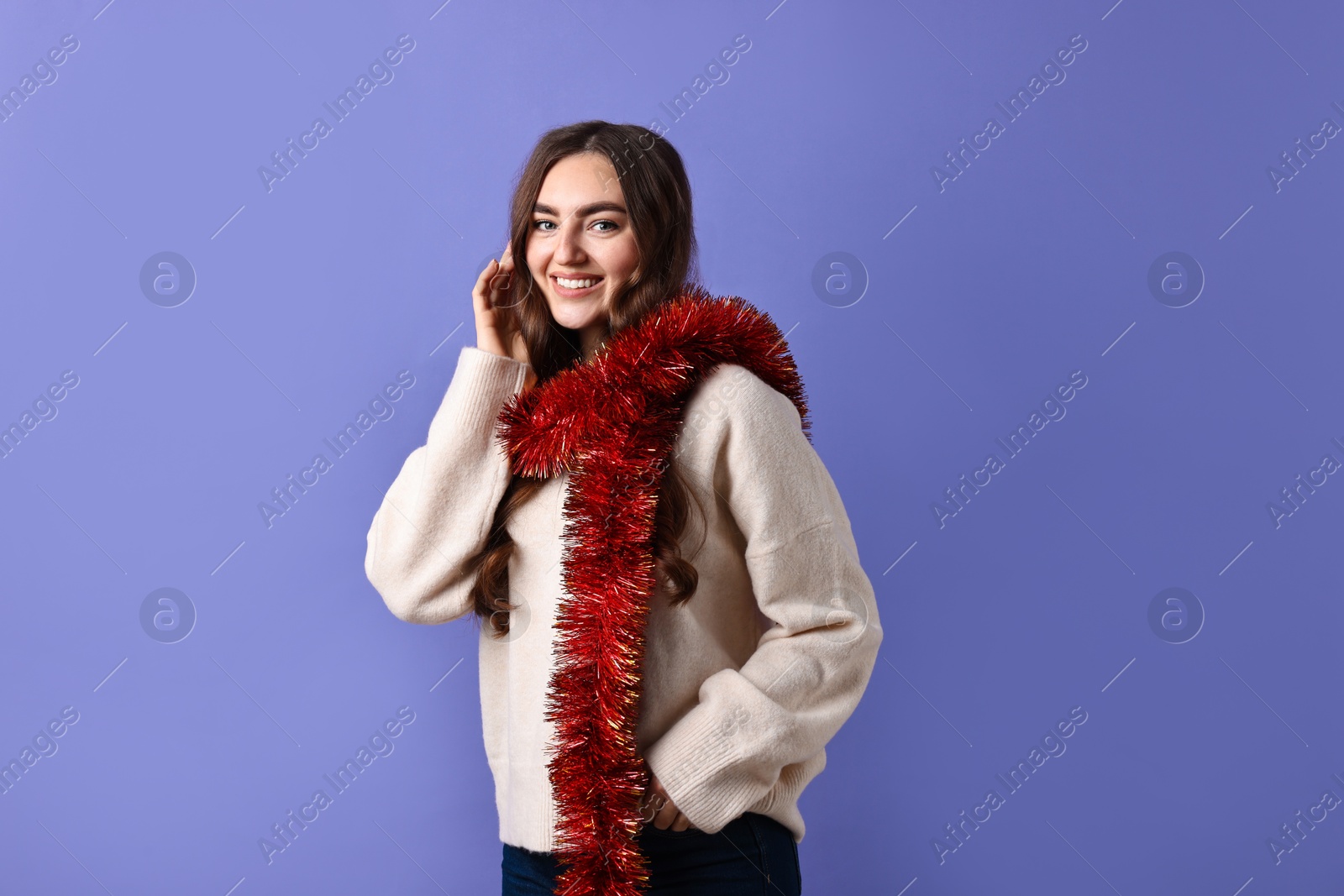 Photo of Happy young woman with tinsel on purple background