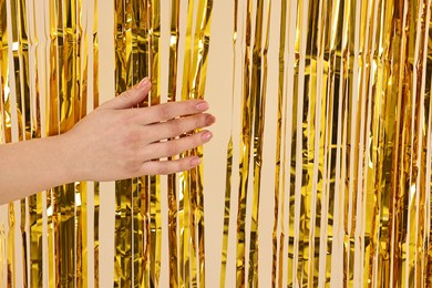 Photo of Woman near golden foil curtain against beige background, closeup