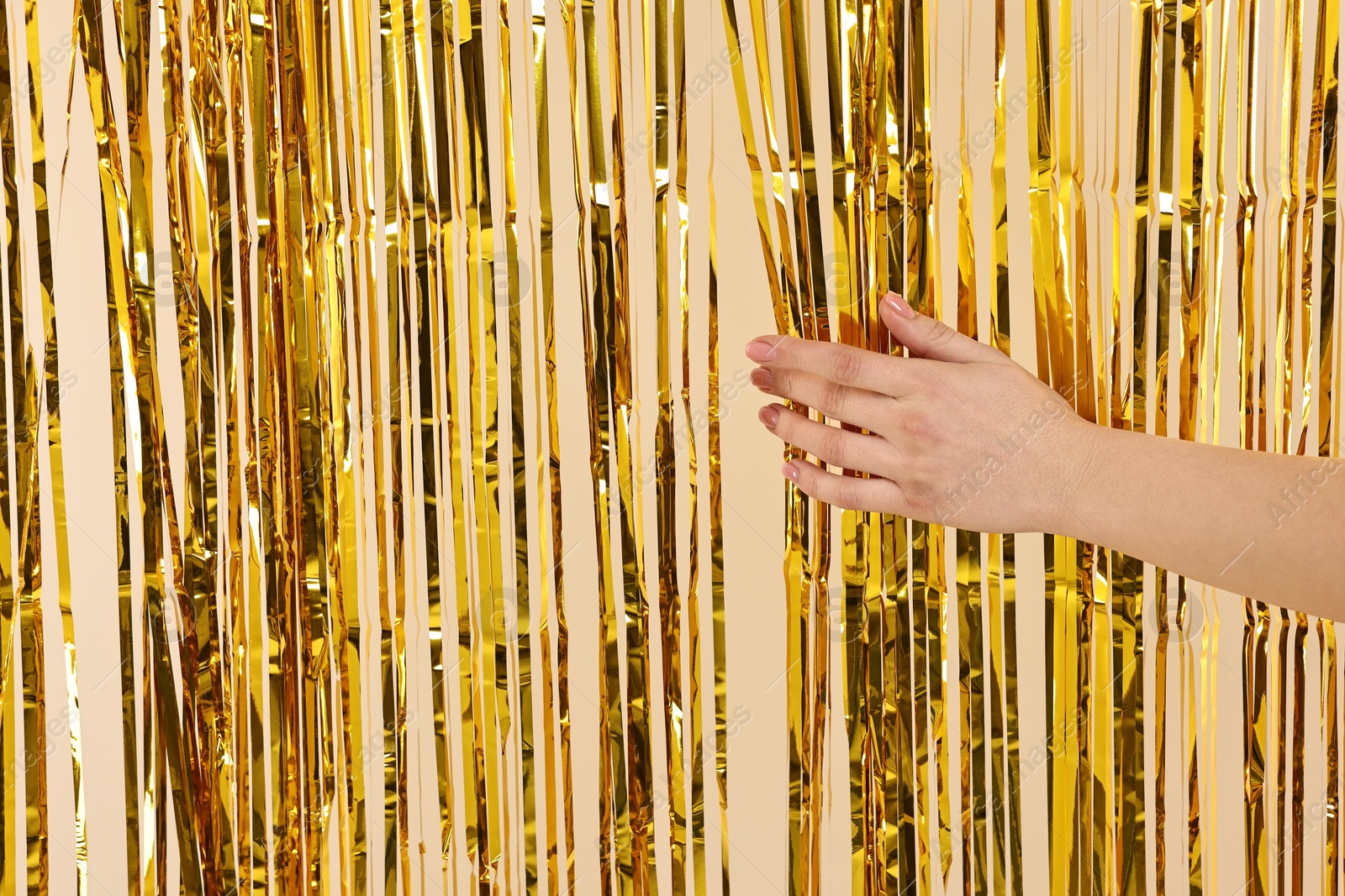 Photo of Woman near golden foil curtain against beige background, closeup