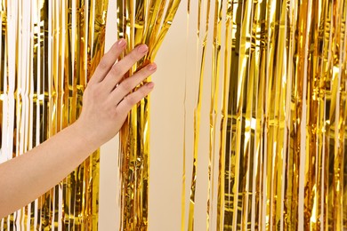 Photo of Woman near golden foil curtain against beige background, closeup