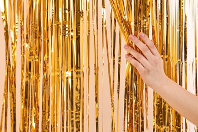 Photo of Woman near golden foil curtain against beige background, closeup