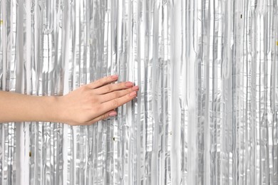 Photo of Woman near silver foil curtain against white background, closeup