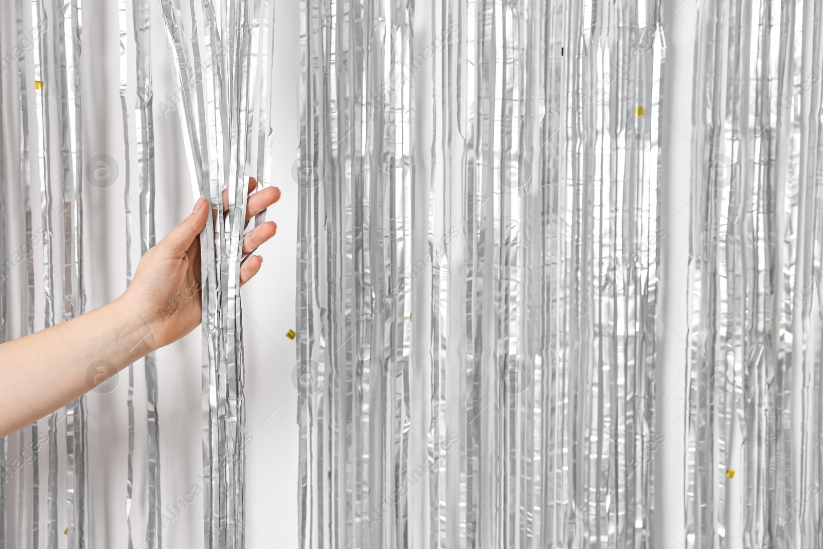 Photo of Woman near silver foil curtain against white background, closeup