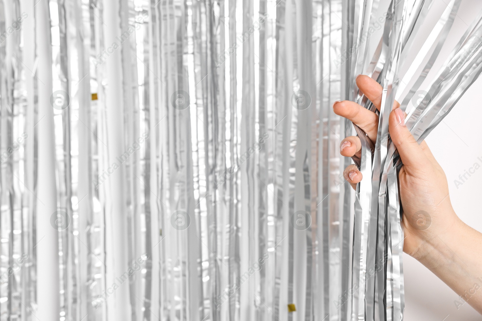 Photo of Woman near silver foil curtain against white background, closeup