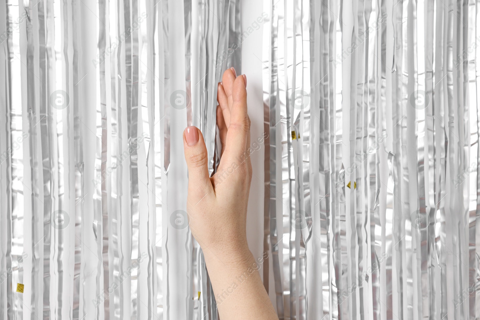 Photo of Woman near silver foil curtain against white background, closeup