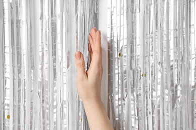 Photo of Woman near silver foil curtain against white background, closeup