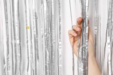 Photo of Woman near silver foil curtain against white background, closeup