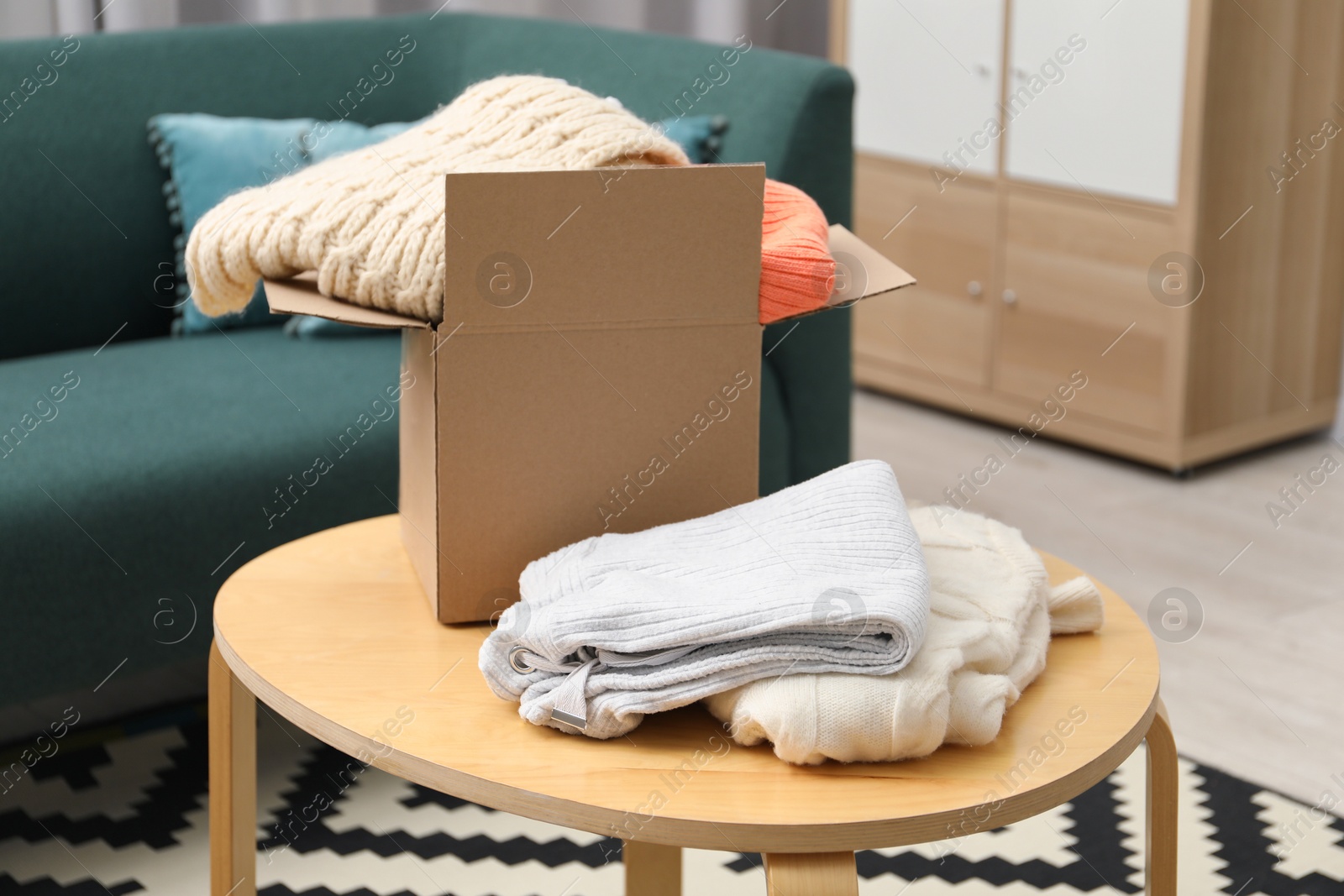 Photo of Different used clothes and box on coffee table indoors