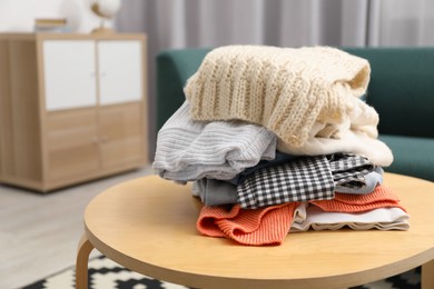 Photo of Stack of different used clothes on coffee table indoors, closeup