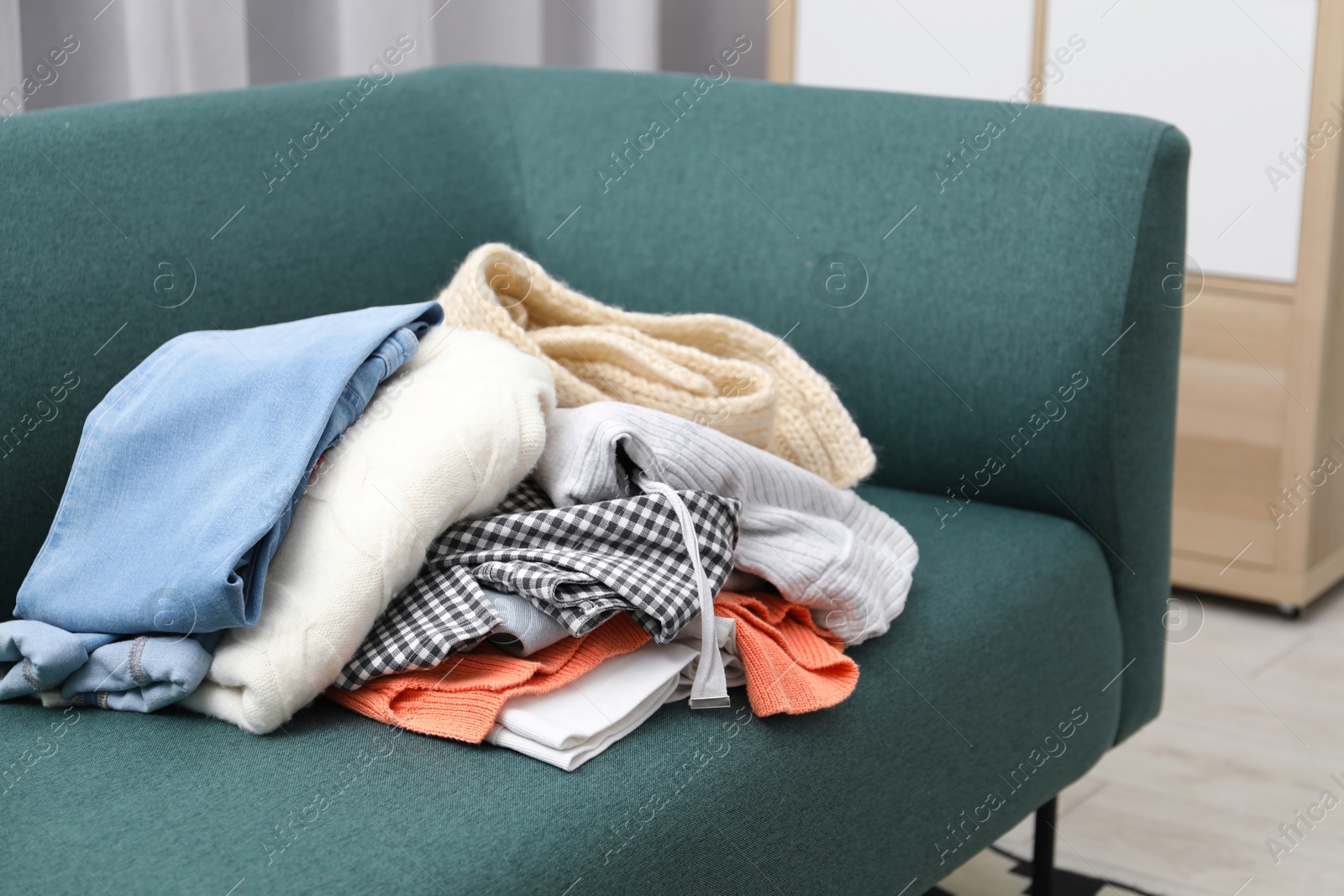 Photo of Pile of different used clothes on sofa indoors