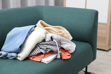 Photo of Pile of different used clothes on sofa indoors