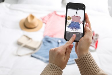 Woman with smartphone taking photo of her used clothes indoors, selective focus