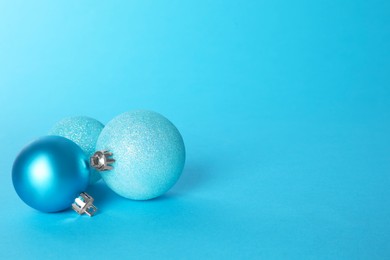 Photo of Beautiful Christmas balls on light blue background, space for text